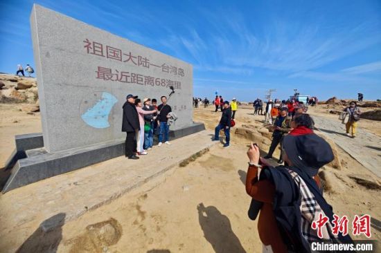 3月1日，福建平潭68海里景区，游客与刻有“祖国大陆——台湾岛最近距离68海里”字样的石碑合影留念。68海里景区，以猴研岛为核心，是中国大陆离台湾岛最近的地方，与台湾新竹南寮渔港相距68海里。中新社记者 王东明 摄